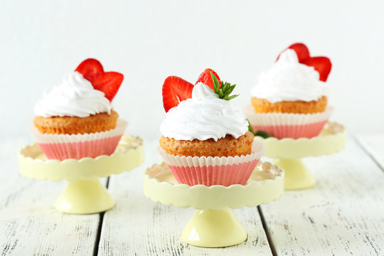 Tasty cupcake with strawberry on cake stand on white wooden back