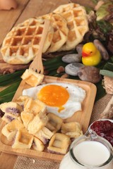 Sweet waffles and fresh milk with jam and egg heart.
