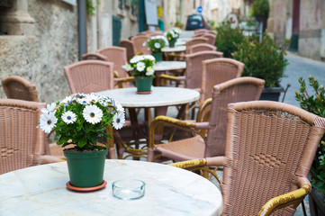 Fototapeta na wymiar Vase with white daisies on the table of a restaurant along the alleys in Ortigia, the old Syracuse