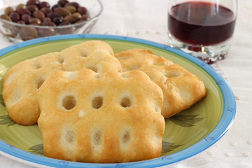 Focaccia with background of black olives and glass of wine