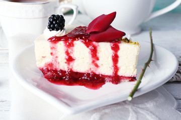 Tasty piece of cheesecake with berry sauce on plate on table close up