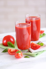 Tomato juice and fresh tomatoes on wooden table close-up
