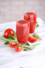 Tomato juice and fresh tomatoes on wooden table close-up