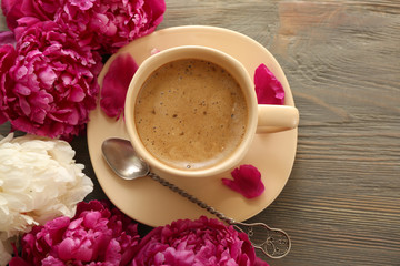Composition with cup of coffee and peony flowers on wooden background