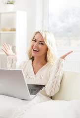 Beautiful thoughtful woman sitting on the sofa using laptop.