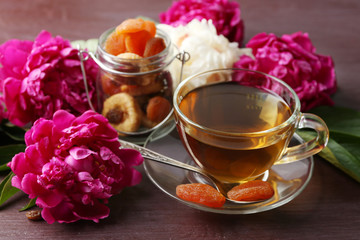 Composition with cup of herbal tea and peony flowers on wooden background