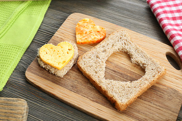 Bread slice with cut in shape of heart and cheese on table close up