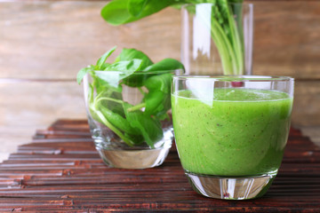 Glass of green healthy juice with spinach and basil on table close up