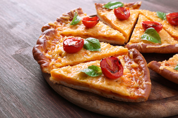 Slices of tasty cheese pizza with basil and cherry tomatoes on table close up