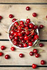 Sweet cherries in bowl on wooden table close up