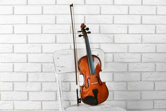 Violin on chair, on bricks wall background