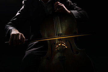 Man playing on cello on dark background