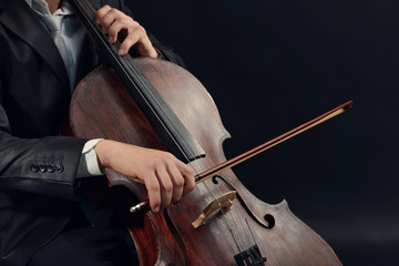 Man playing on cello on dark background