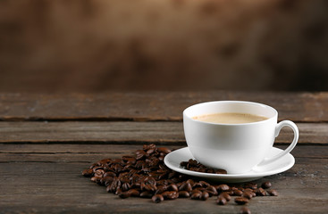 Cup of coffee and beans on blurred background