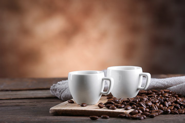 Cups of coffee and beans on blurred background