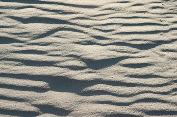 Close-up of beach sand texture with shadows from sunshine