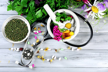 Alternative medicine herbs, berries and stethoscope on wooden table background