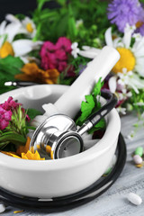 Alternative medicine herbs, berries and stethoscope on wooden table background