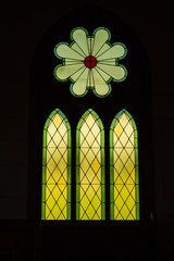 vertical image of a beautiful stained glass church window with outdoor light gleaming through on a...