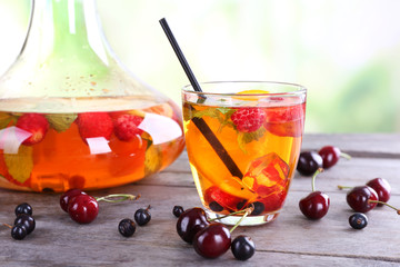 Punch with berries in glassware on wooden table on light blurred background