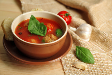 Tomato soup with meat balls on wooden spoon on wooden background