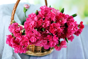 Beautiful bouquet of pink carnation in basket on bright background