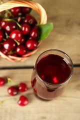 Glass of fresh juice with cherries on wooden table close up