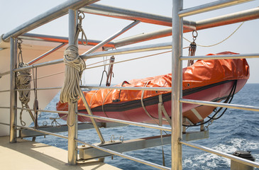 orange lifeboat hanging on ship at sea
