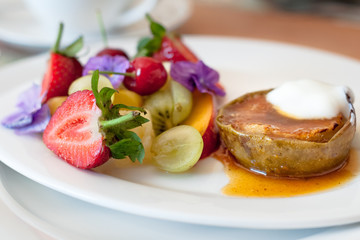 Warm, spicy baked apple with honey caramel sauce and bulgarian yoghurt, and fresh fruit decorated with edible purple flowers. Regional cuisine with a modern twist. Served in bed and breakfast inn.