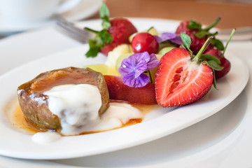 Warm, spicy baked apple with honey caramel sauce and bulgarian yoghurt, and fresh fruit decorated with edible purple flowers. Regional cuisine with a modern twist. Served in bed and breakfast inn.