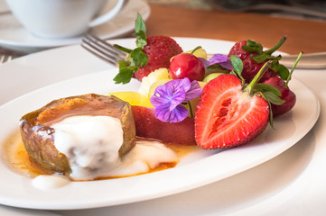 Warm, spicy baked apple with honey caramel sauce and bulgarian yoghurt, and fresh fruit decorated with edible purple flowers. Regional cuisine with a modern twist. Served in bed and breakfast inn.
