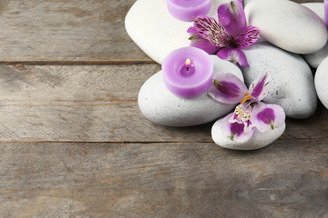 Spa still life with purple flowers, pebbles and candlelight on wooden background