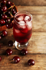 Glass of cherry juice on wooden background