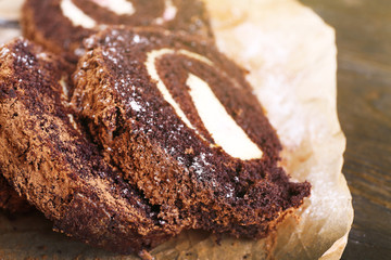 Delicious chocolate roll on parchment, closeup