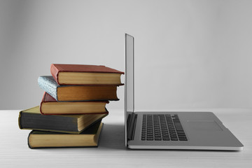 Stack of books with laptop on gray background