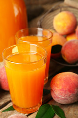 Ripe peaches and glass of juice on wooden background