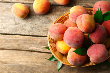 Ripe peaches in basket on wooden background