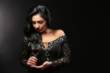 Pretty young woman with wineglass on black background
