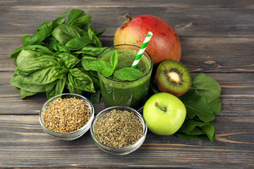 Green healthy juice with fruits and herbs on wooden table close up