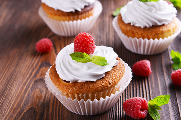 Delicious cupcakes with berries and fresh mint on wooden table close up