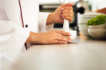 Obraz premium Cook hands with mortar with herbs on bright background
