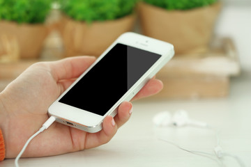 Music smartphone in female hand, on light background