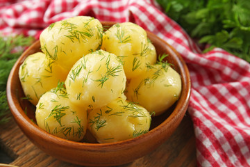 Boiled potatoes with greens in bowl on table close up