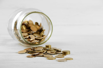 Coins in money jar on wooden background