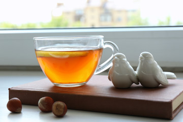 Cup of tea with book on windowsill, closeup