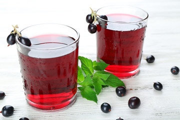 Glasses of fresh blackcurrant juice wooden table background