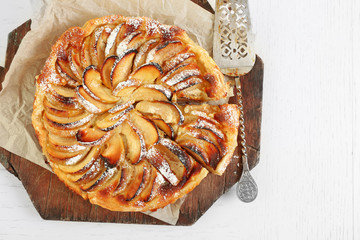 Homemade apple pie on cutting board on white wooden table background background