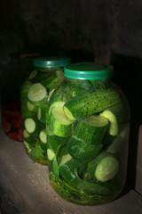 Home preserved cucumbers in glass jars in cellar, closeup