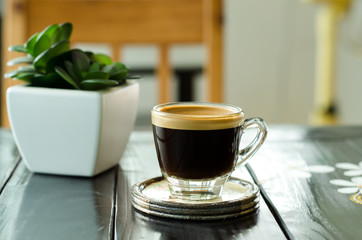 The cup of coffee (espresso) on the wooden table in the coffee shop