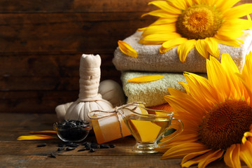 Spa treatments and sunflower on wooden background